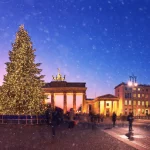 Brandenburger Tor i Berlin med juletræ og faldende sne om aftenen